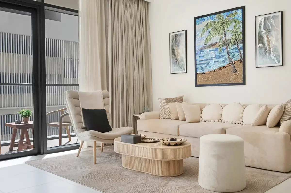 Bright living room with a beige sofa, framed art and a balcony